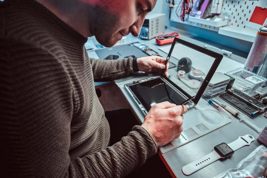 The technician repairs a broken tablet computer in a repair shop